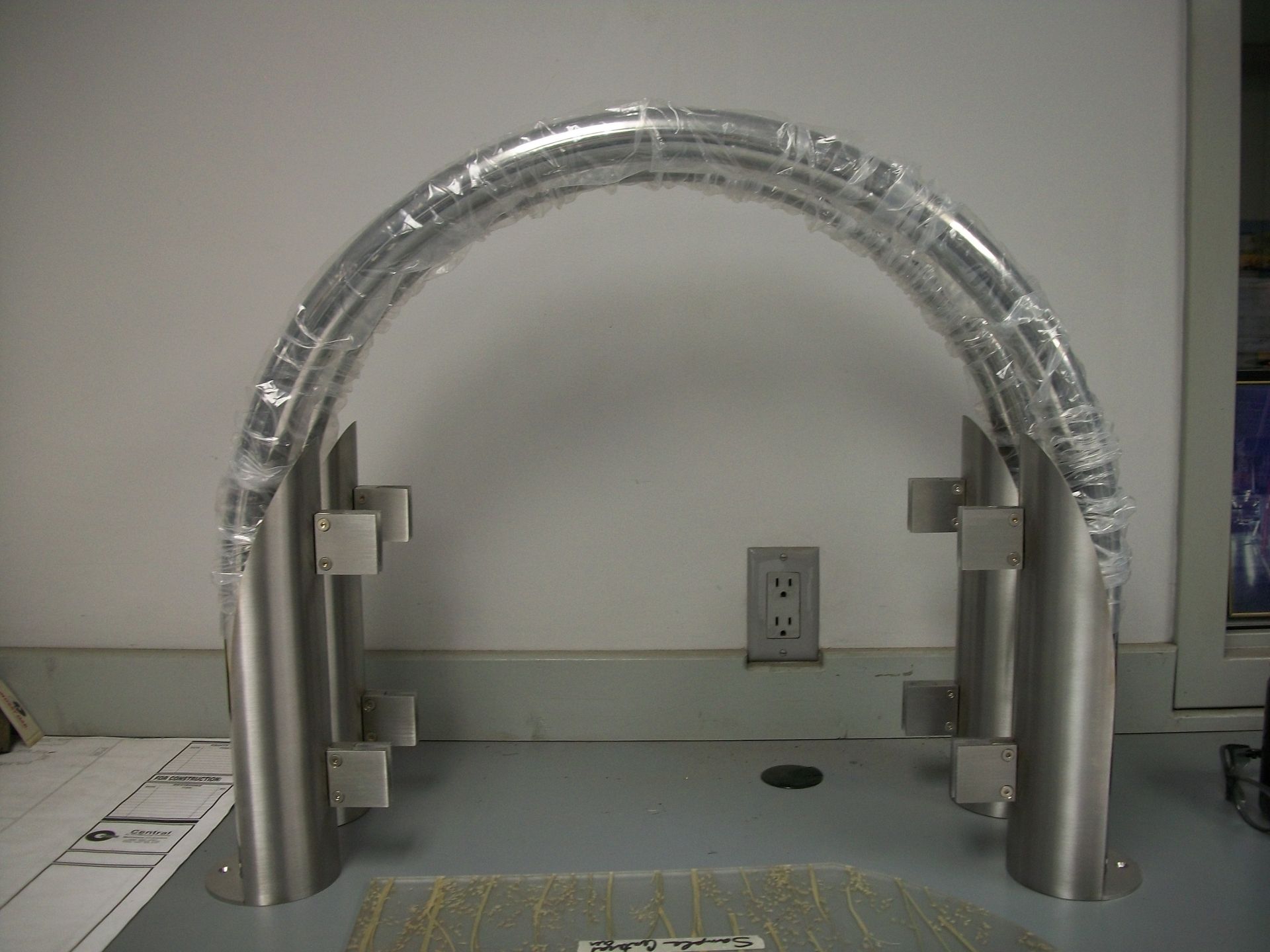 A metal arch is wrapped in plastic and sitting on a table