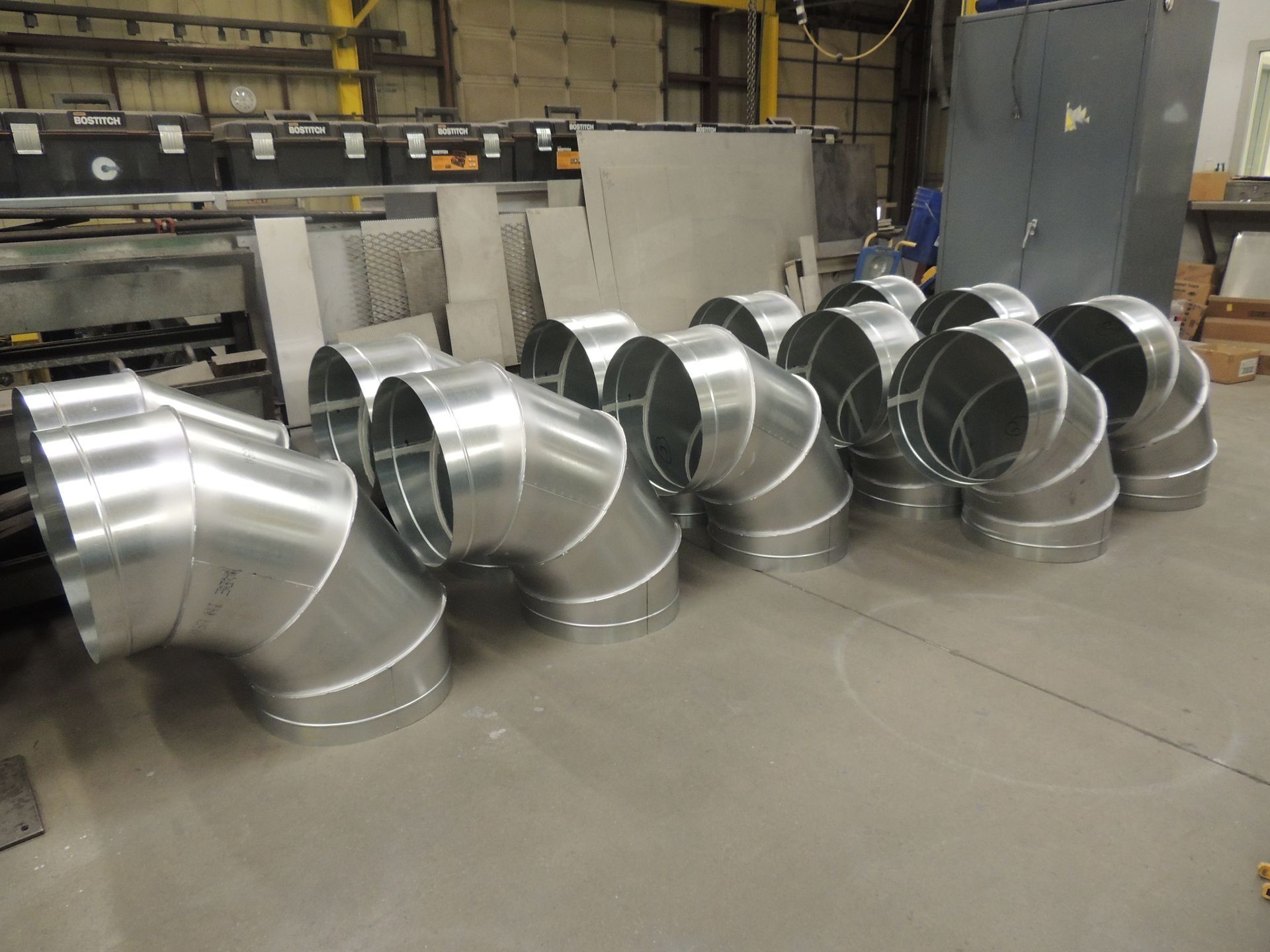 A bunch of metal pipes are sitting on the floor in a warehouse.
