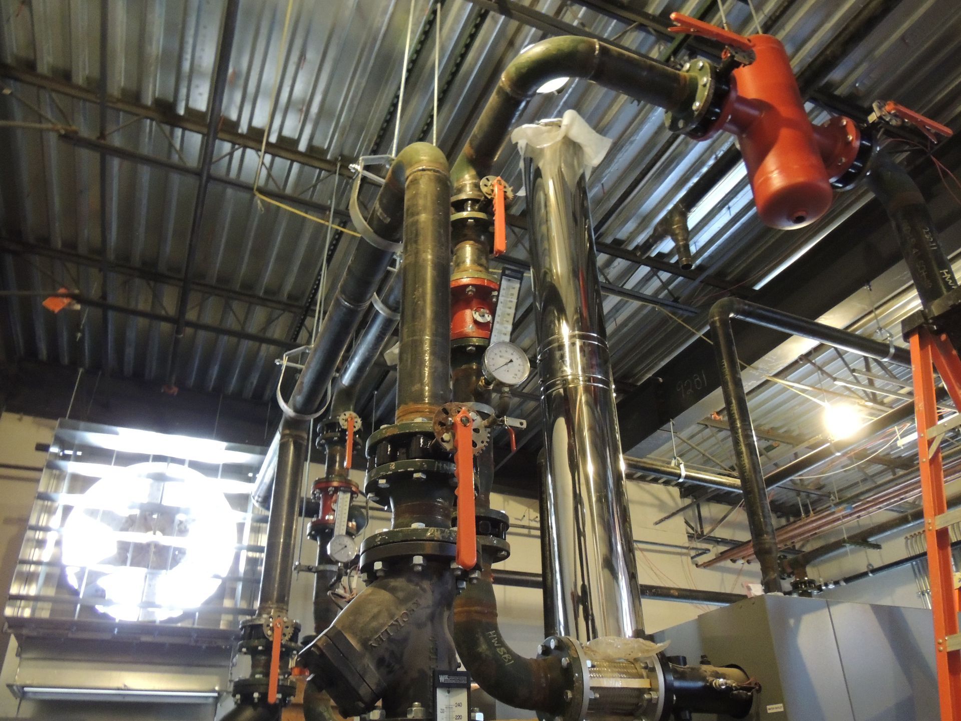 A bunch of pipes are hanging from the ceiling of a building