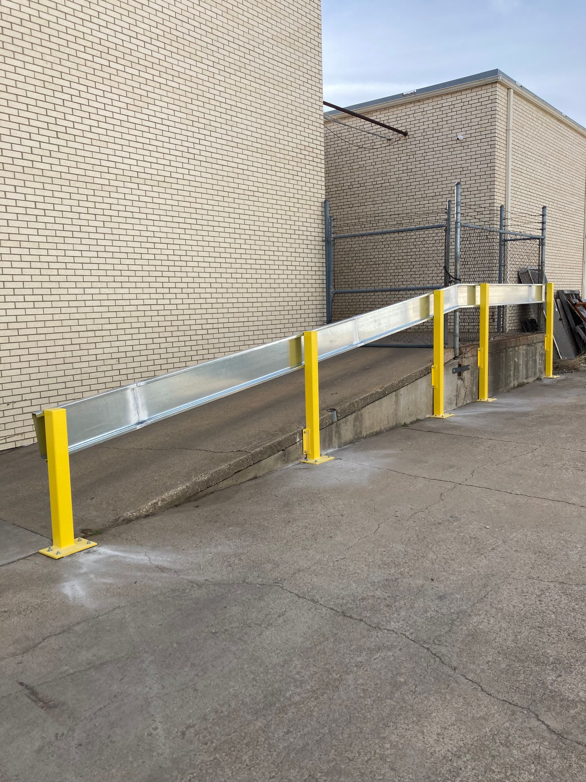 A ramp with yellow poles leading to a building