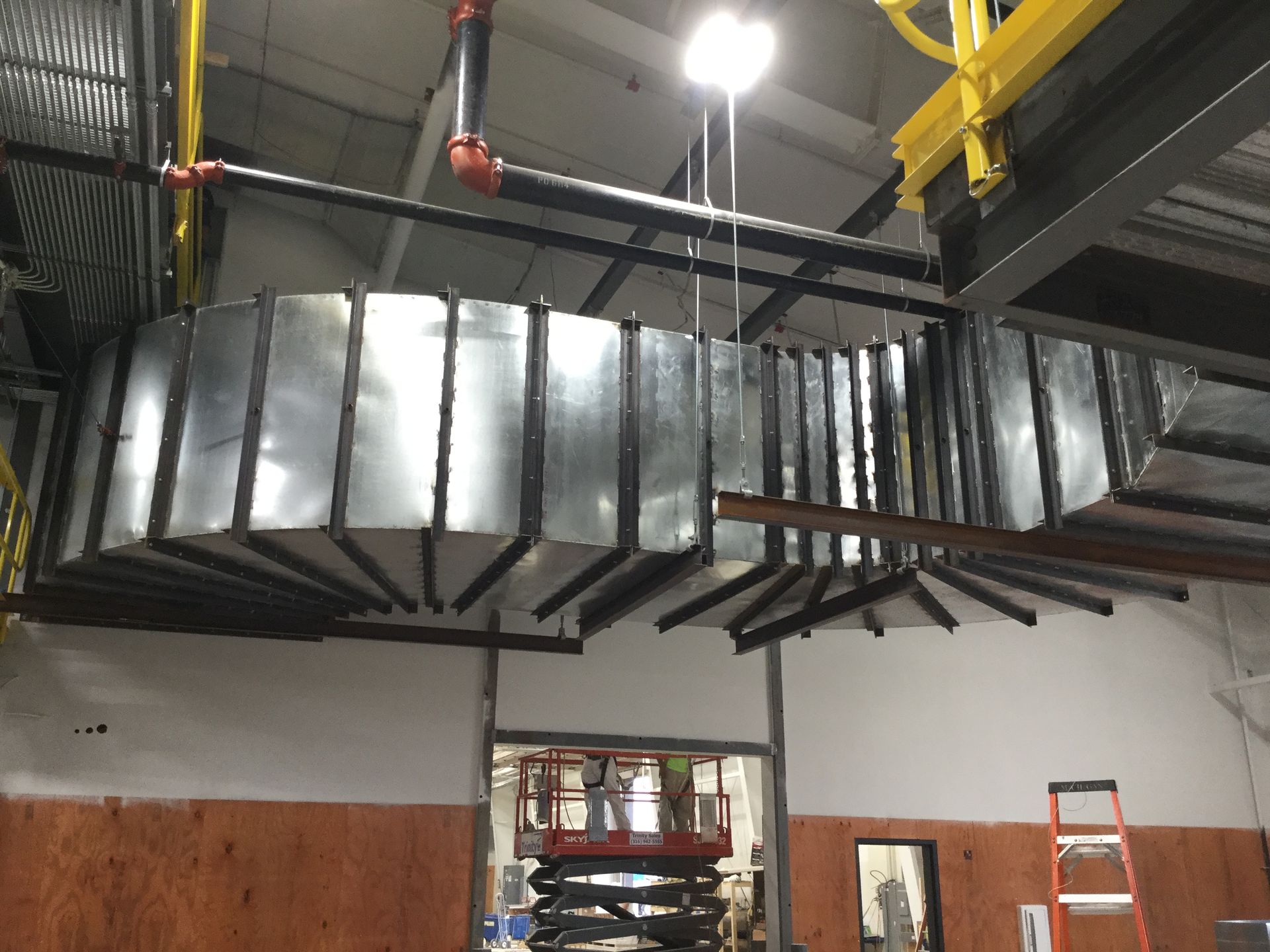 A large metal pipe is hanging from the ceiling of a building.