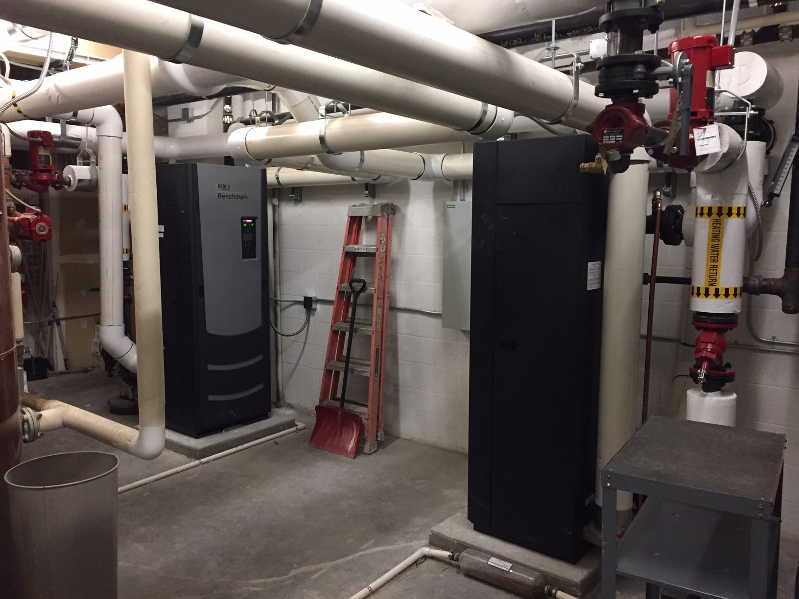 A room with a lot of pipes and a ladder