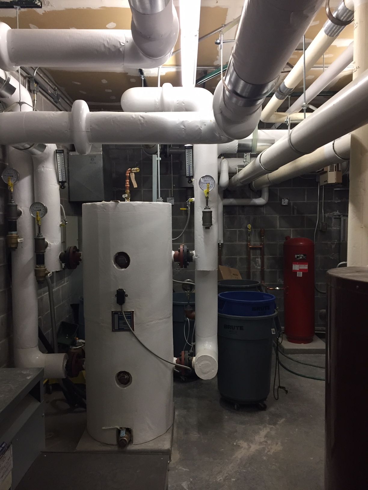 A room with a lot of pipes and a water heater