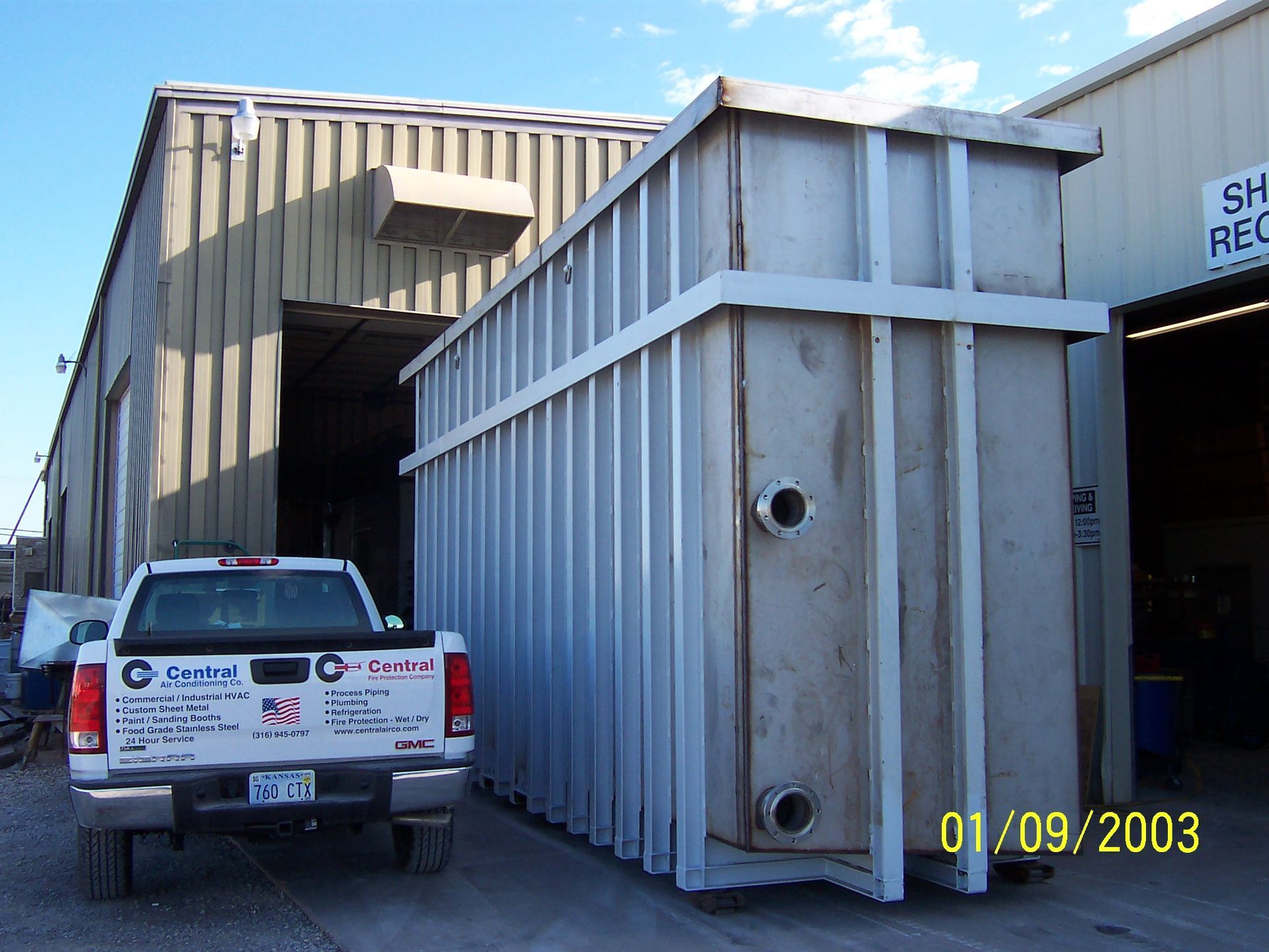 A truck parked in front of a building with the date 01/09/2003