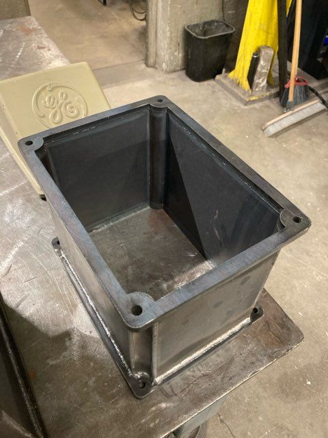 A metal box is sitting on top of a metal table.