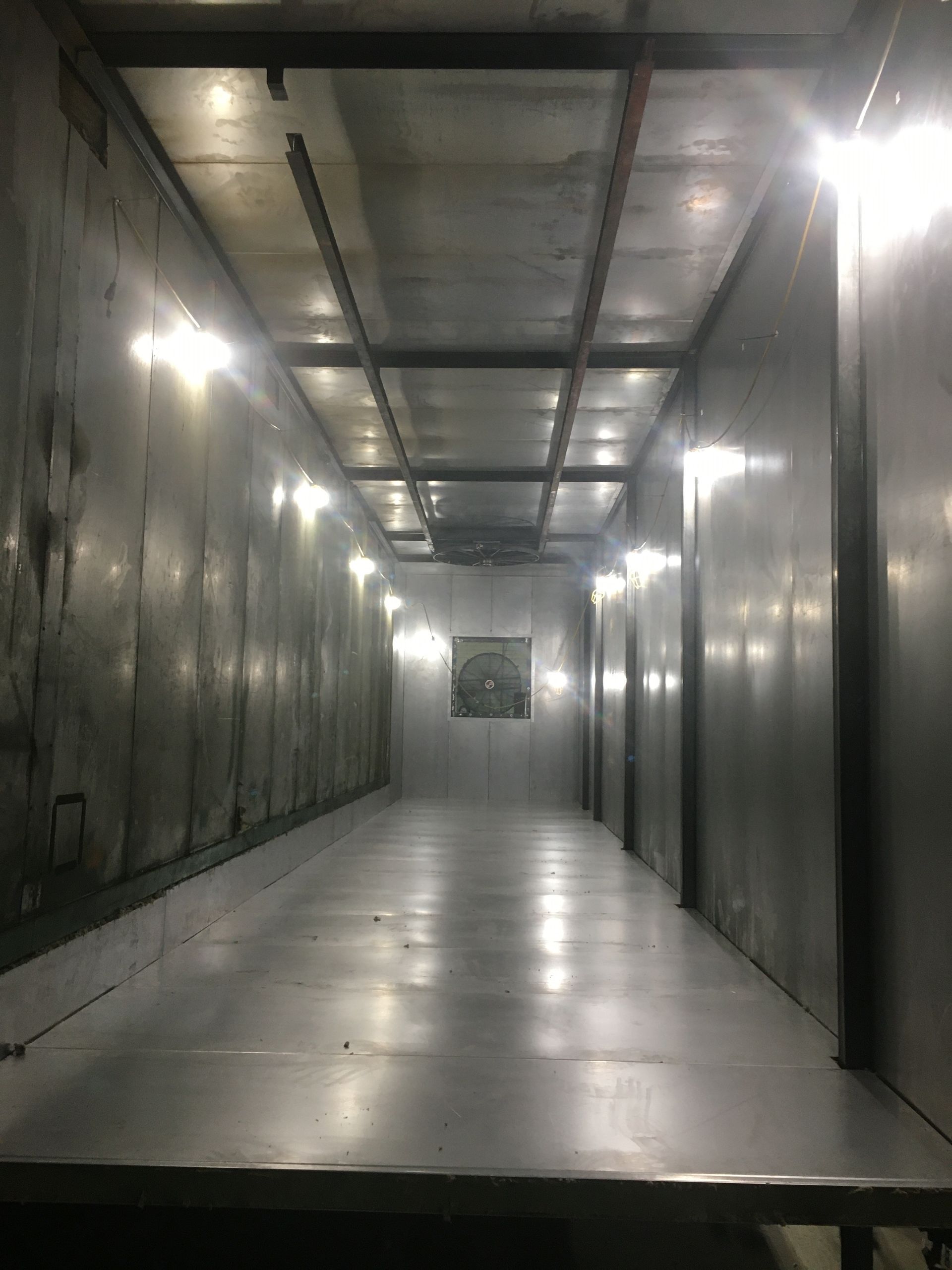 A long empty room with a lot of lights on the ceiling.