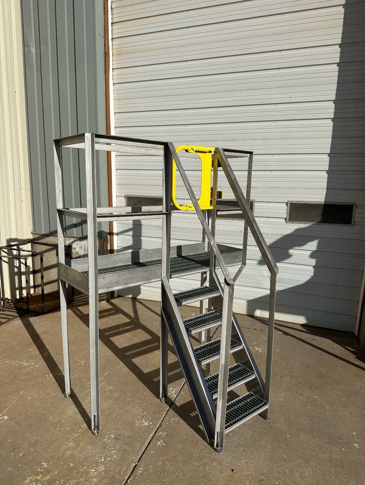 A metal staircase with a yellow railing is sitting in front of a garage door.