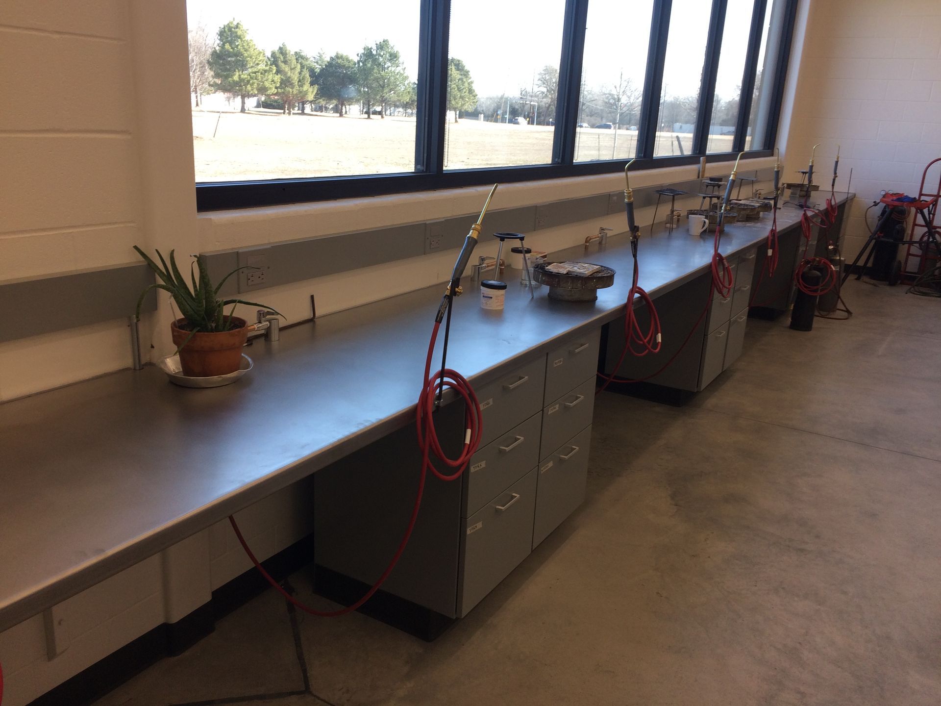 A row of stainless steel tables in a room with a window.