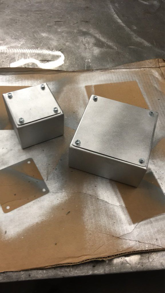 Two metal boxes are sitting on top of a piece of cardboard.