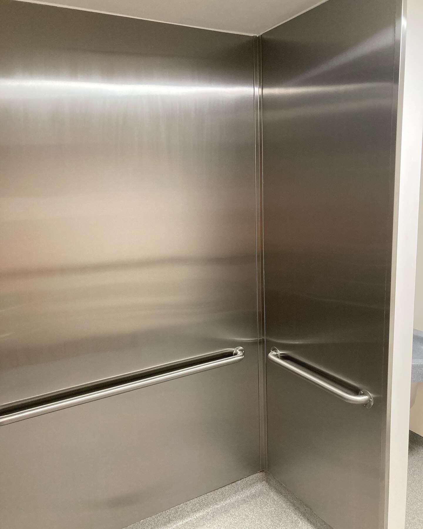 The inside of an elevator with stainless steel walls and handles.