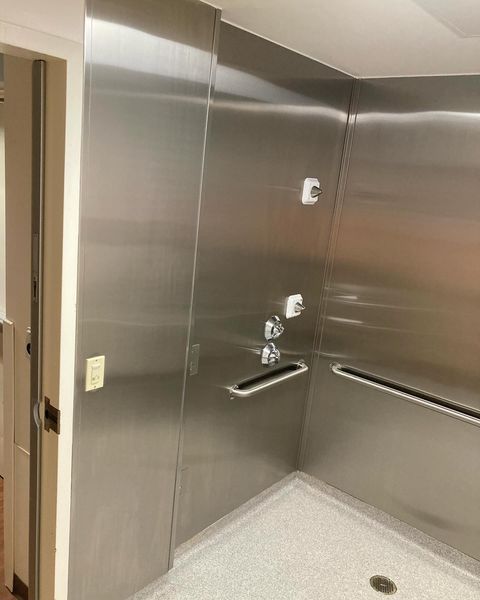 A bathroom with stainless steel walls and a walk in shower.