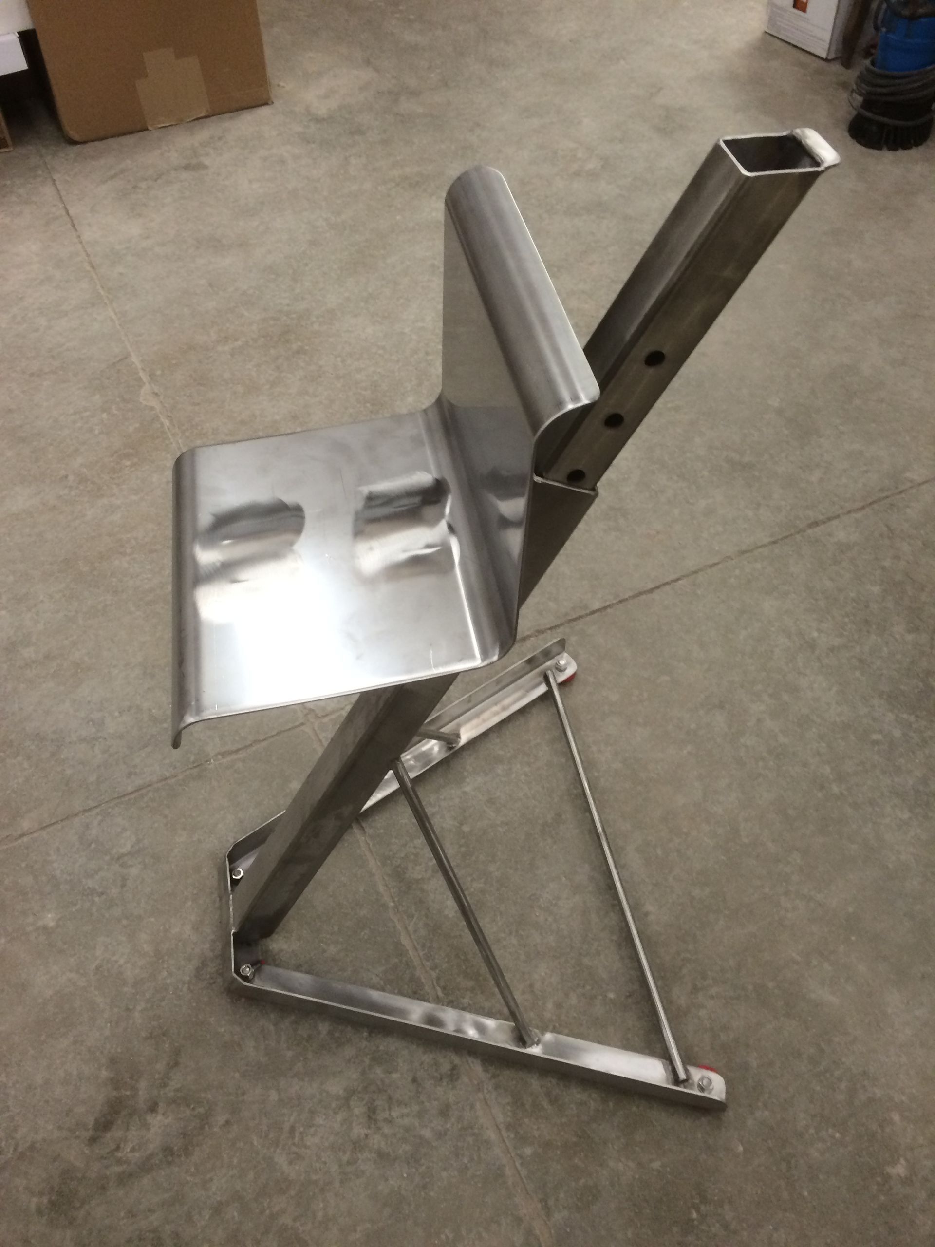 A stainless steel chair is sitting on a concrete floor