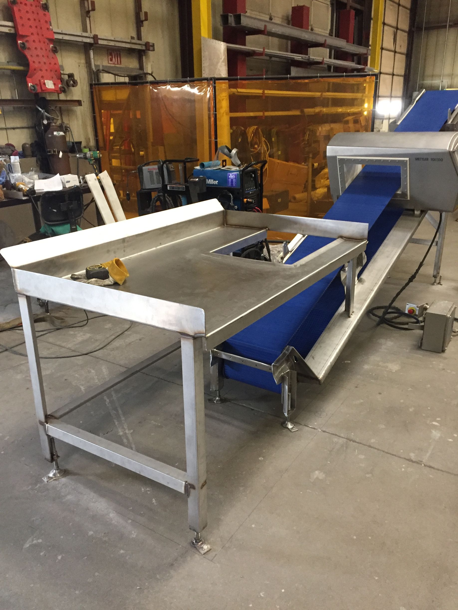 A stainless steel table with a conveyor belt attached to it in a factory.