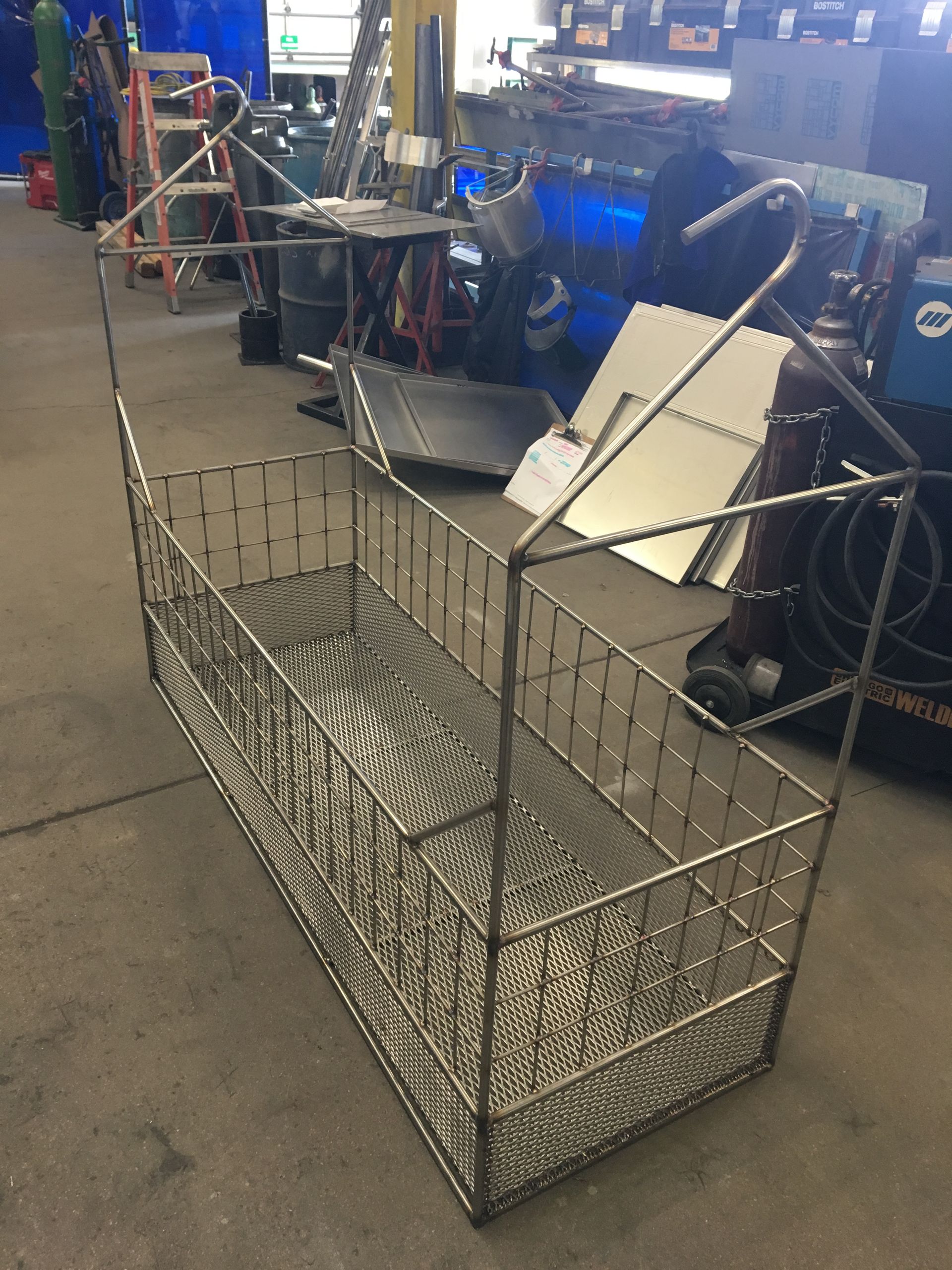 A metal basket is sitting on the floor in a room.