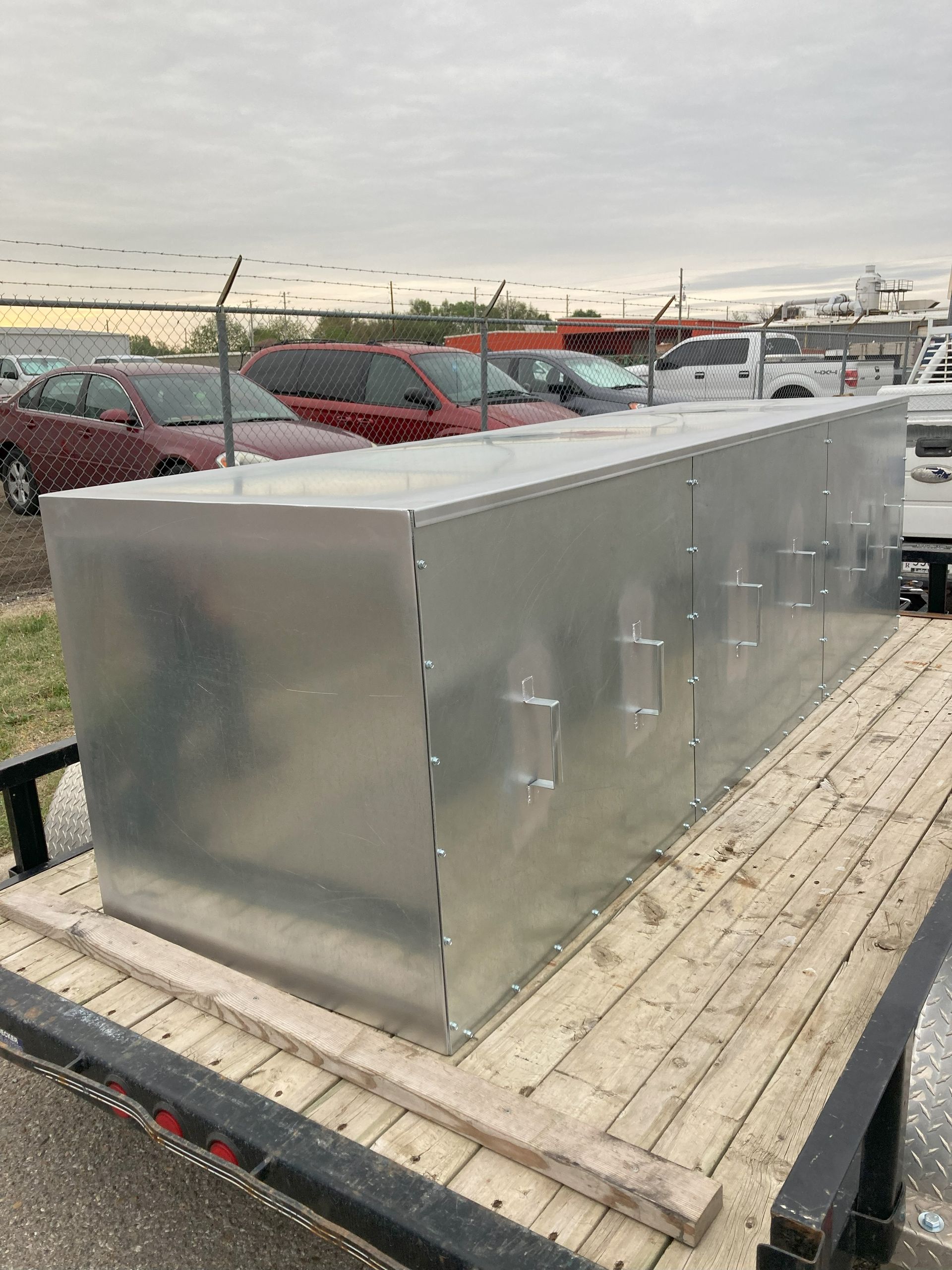 A large metal box is sitting on top of a wooden trailer.