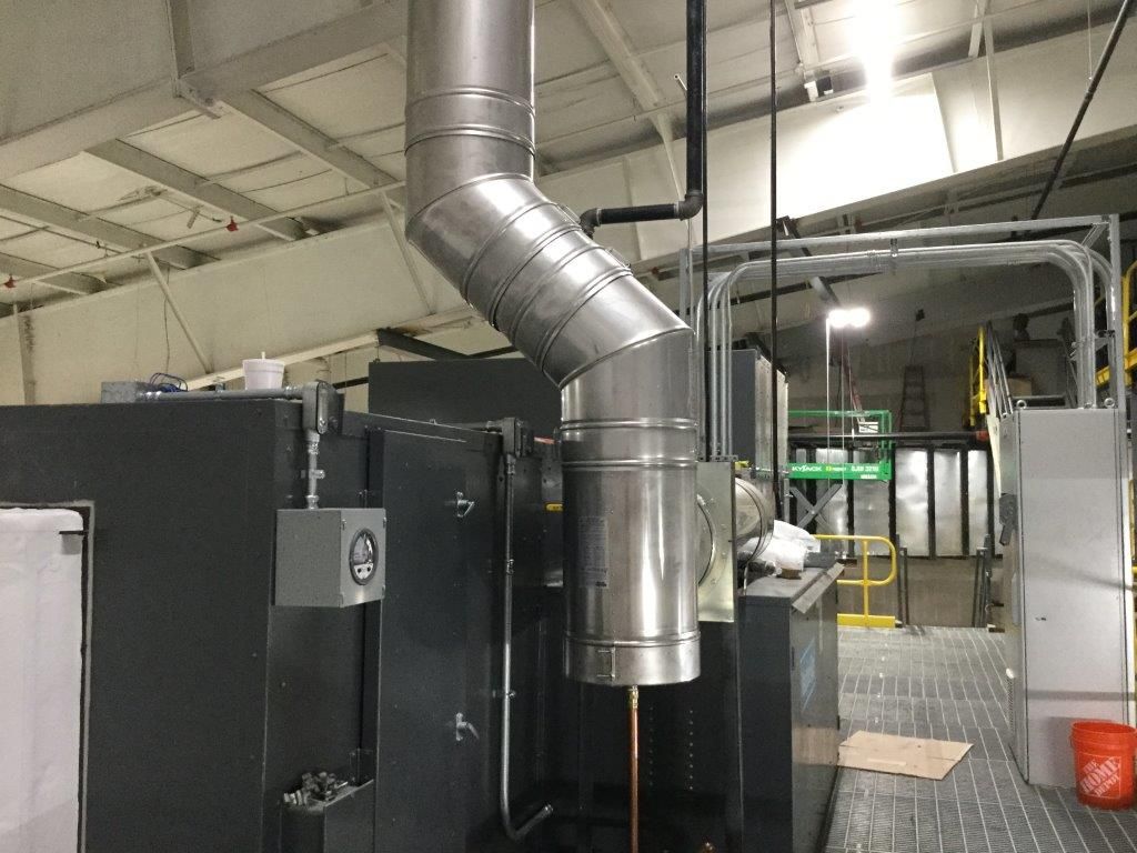 A large metal pipe is hanging from the ceiling in a factory.
