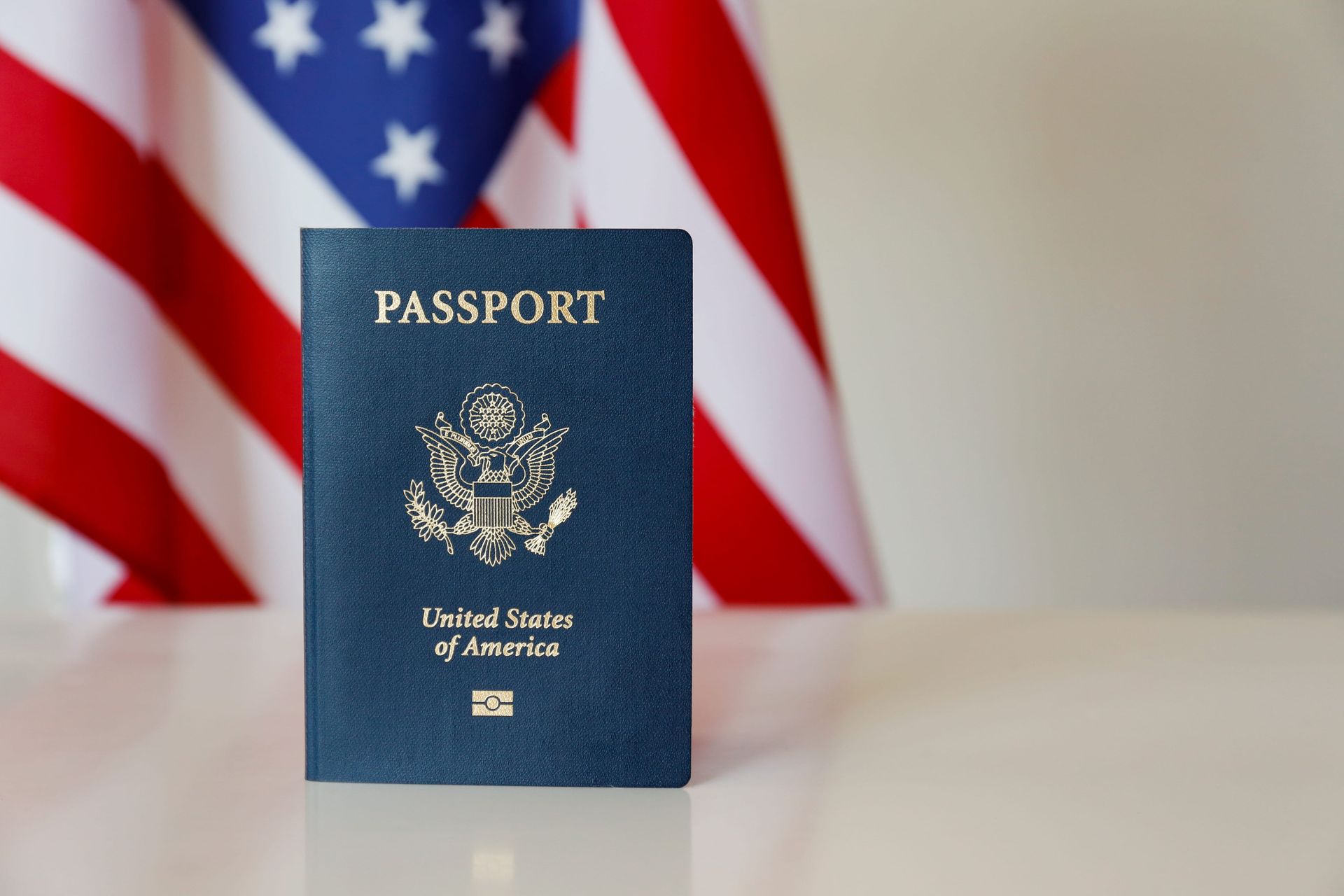 U.S. passport standing in front of a blurred American flag backdrop