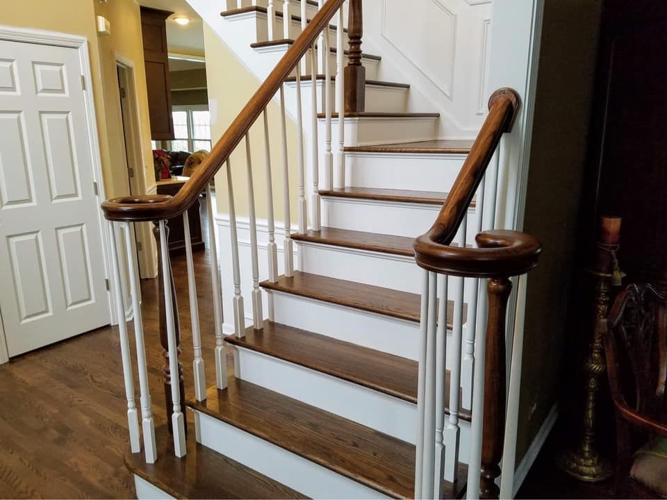 Staircase with white balusters, wooden handrails, and carpeted steps in a home interior
