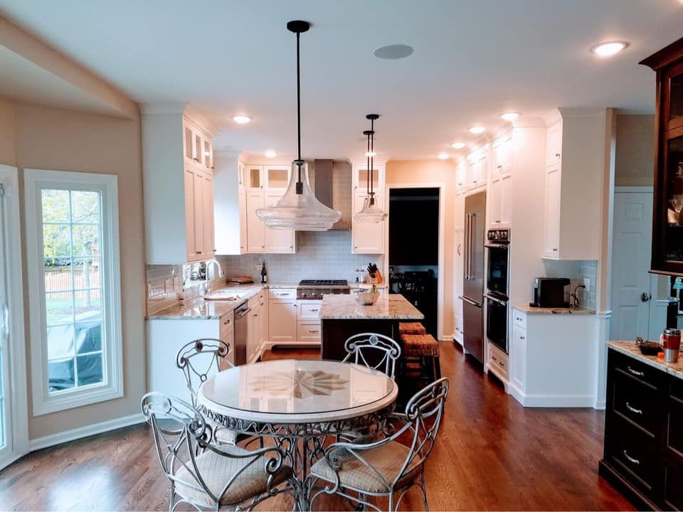 Bright kitchen with white cabinets, wood floors, round table, and stainless steel appliances