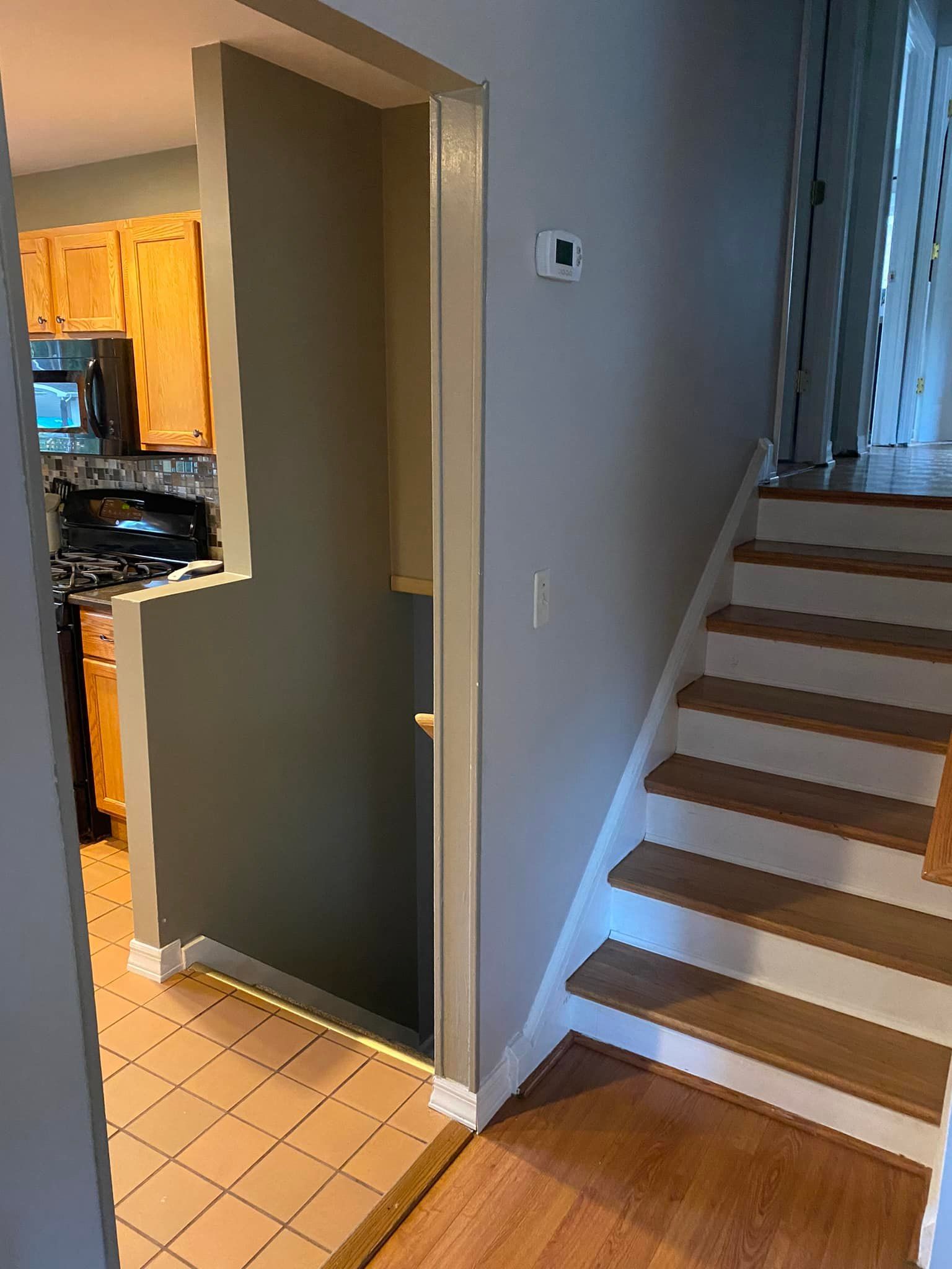 Indoor stairway beside a kitchen doorway, with tiled floor and window light from above