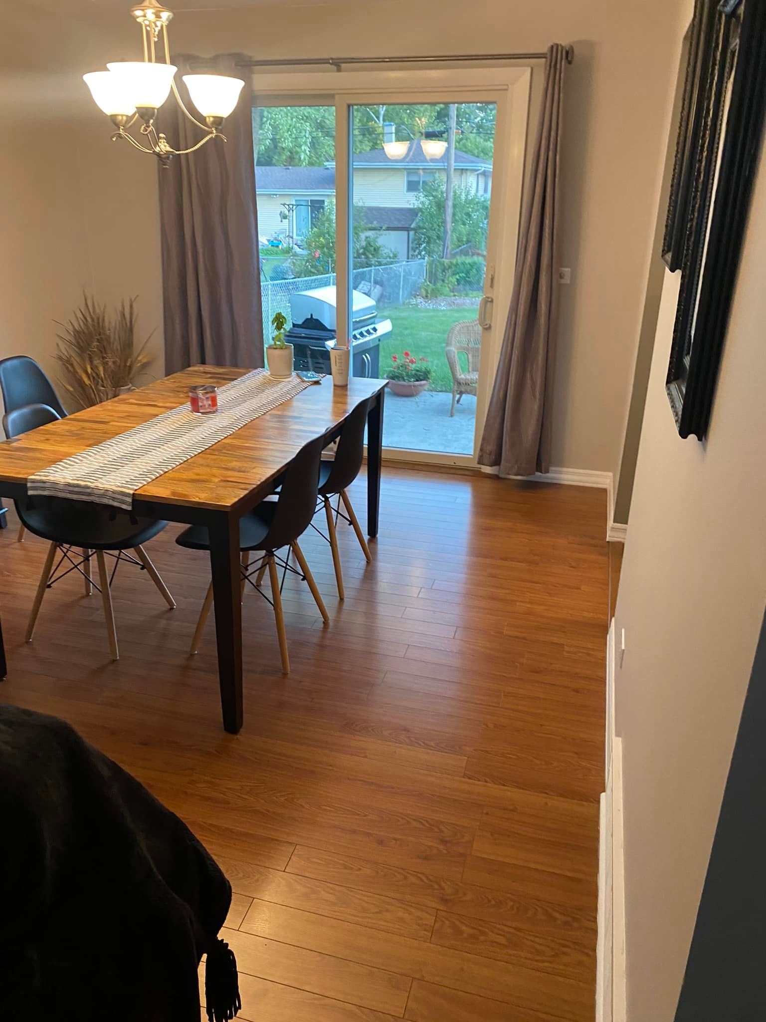 Dining room with wooden table, black chairs, and sliding glass doors opening to a backyard.