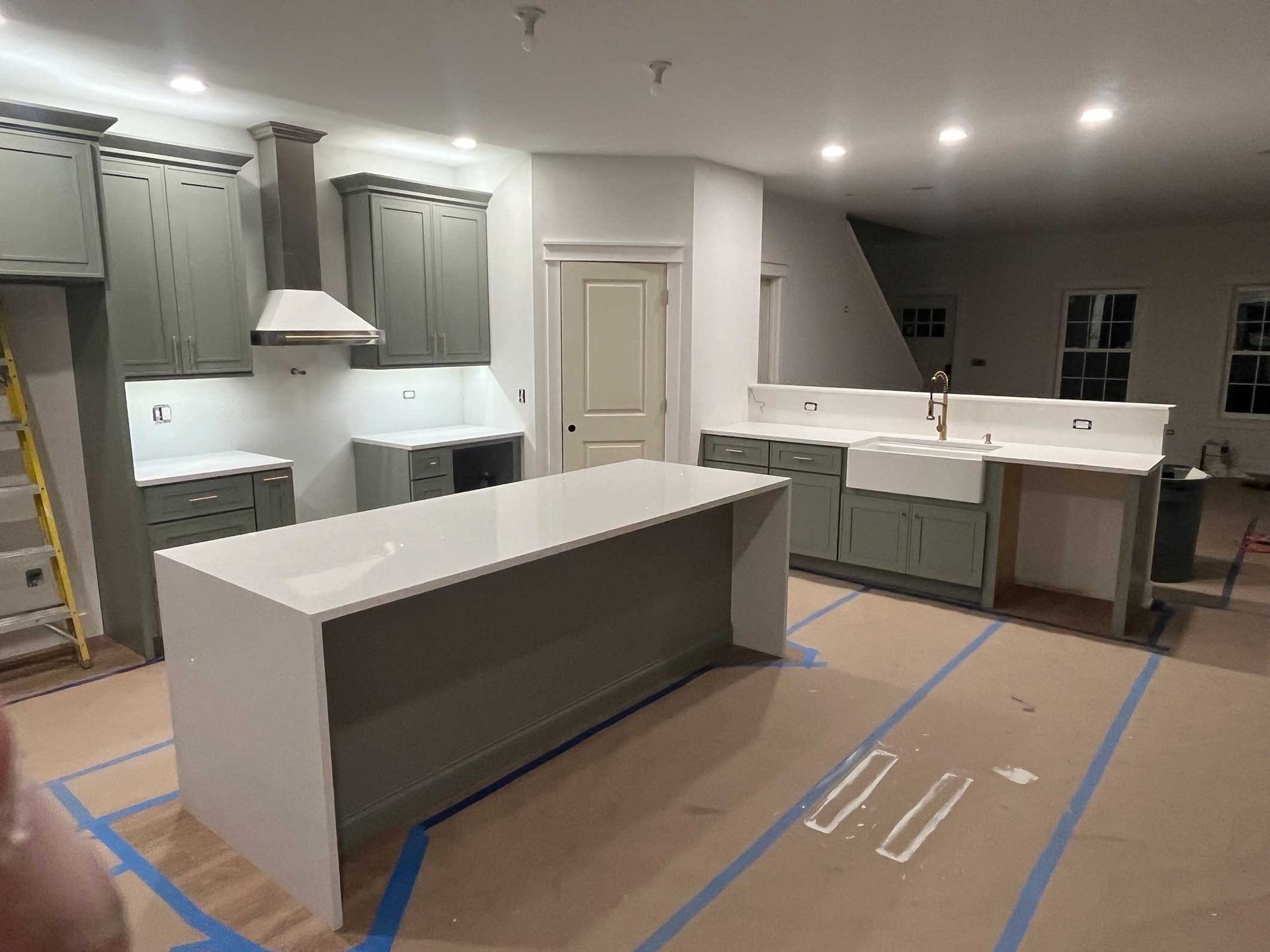 Modern kitchen with gray cabinets, white island, and unfinished flooring in a newly built home