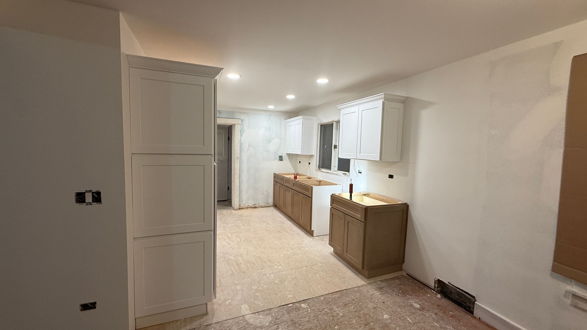 Bright modern kitchen with white cabinets, island, round table, and hardwood floors