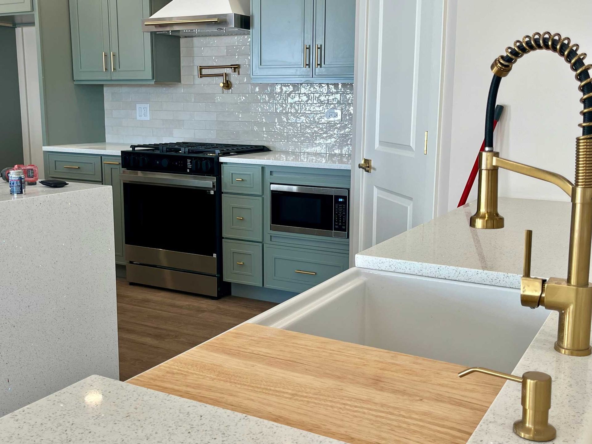 Modern kitchen with black stove, white cabinets, brass faucet, and wood countertops