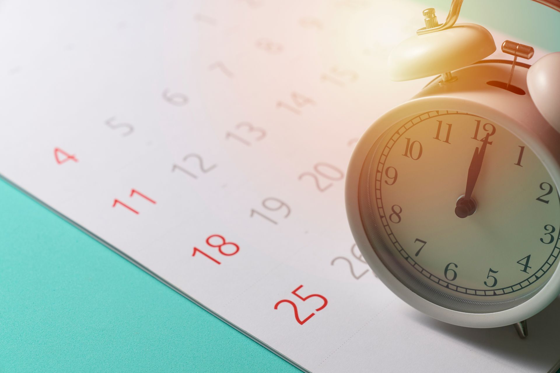 An alarm clock is sitting on top of a calendar.
