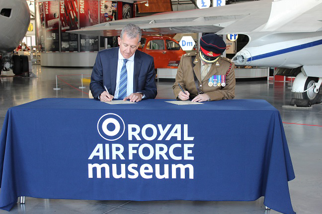 Two men are signing a contract at the royal air force museum