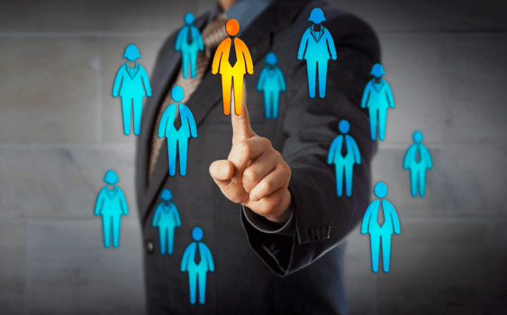 A man in a suit is pointing at a group of people.