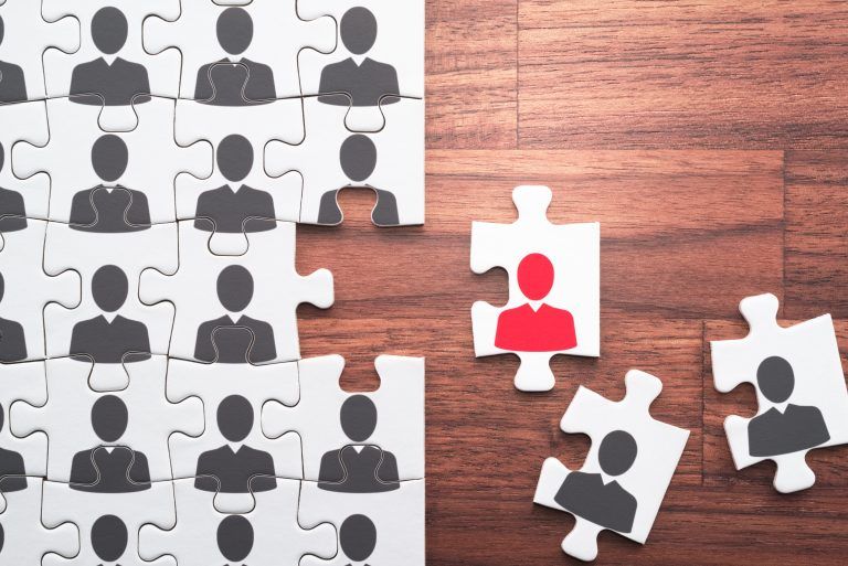 A group of puzzle pieces with people on them on a wooden table.