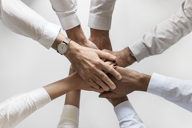 A group of people are putting their hands together in a circle.