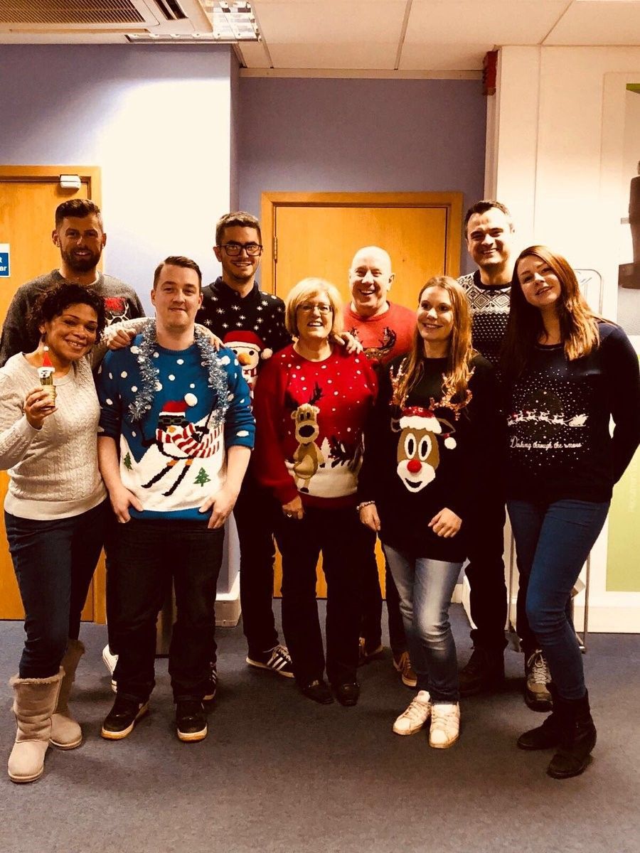 A group of people wearing christmas sweaters are posing for a picture.