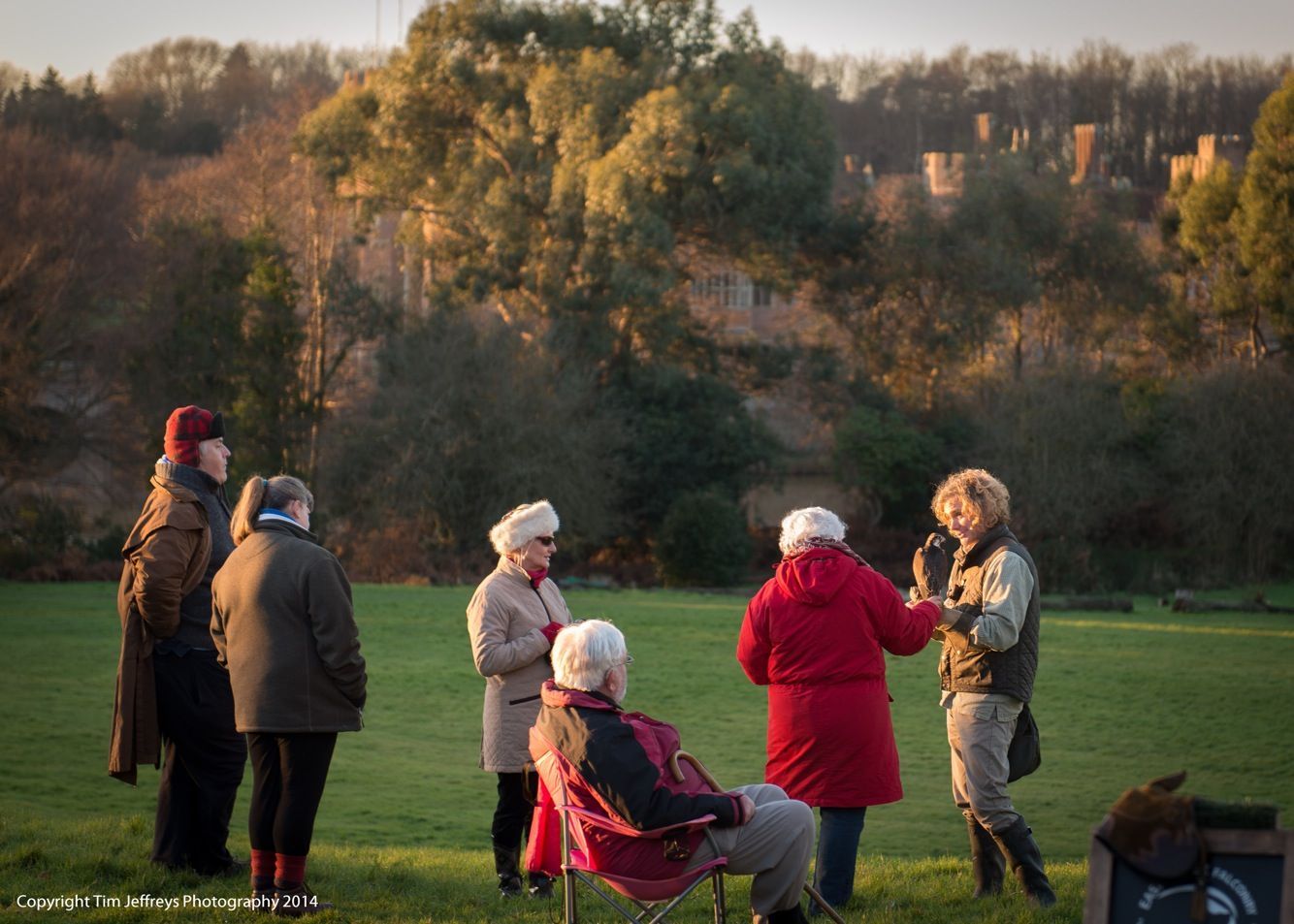 a group of people are standing in a field talking to each other .