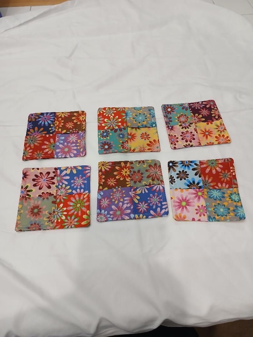 Six colorful floral square cards arranged in two rows on a white fabric surface.
