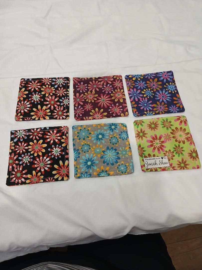 Six colorful floral-pattern fabric squares arranged in two rows on a white bedspread.