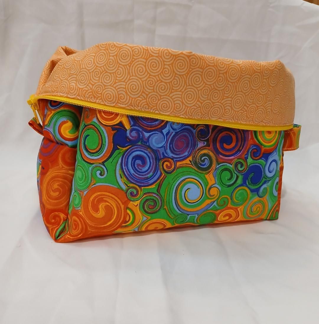 Colorful patterned fabric pouch with orange flap on a white background