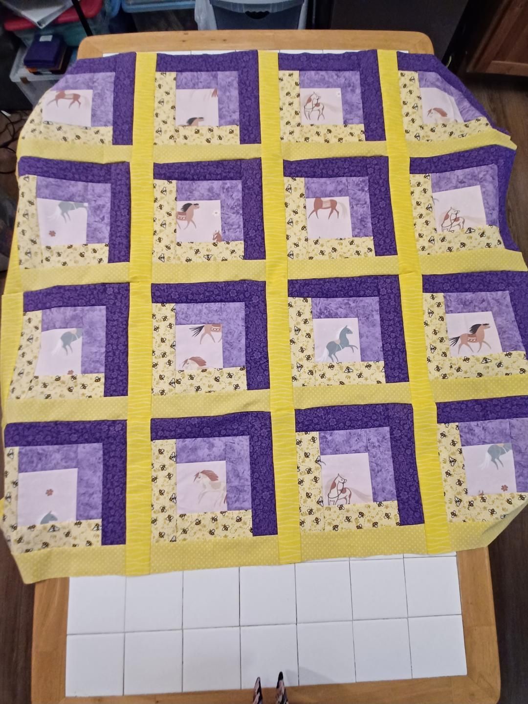 Purple and yellow patchwork quilt spread over a chair, with a white tiled floor visible below