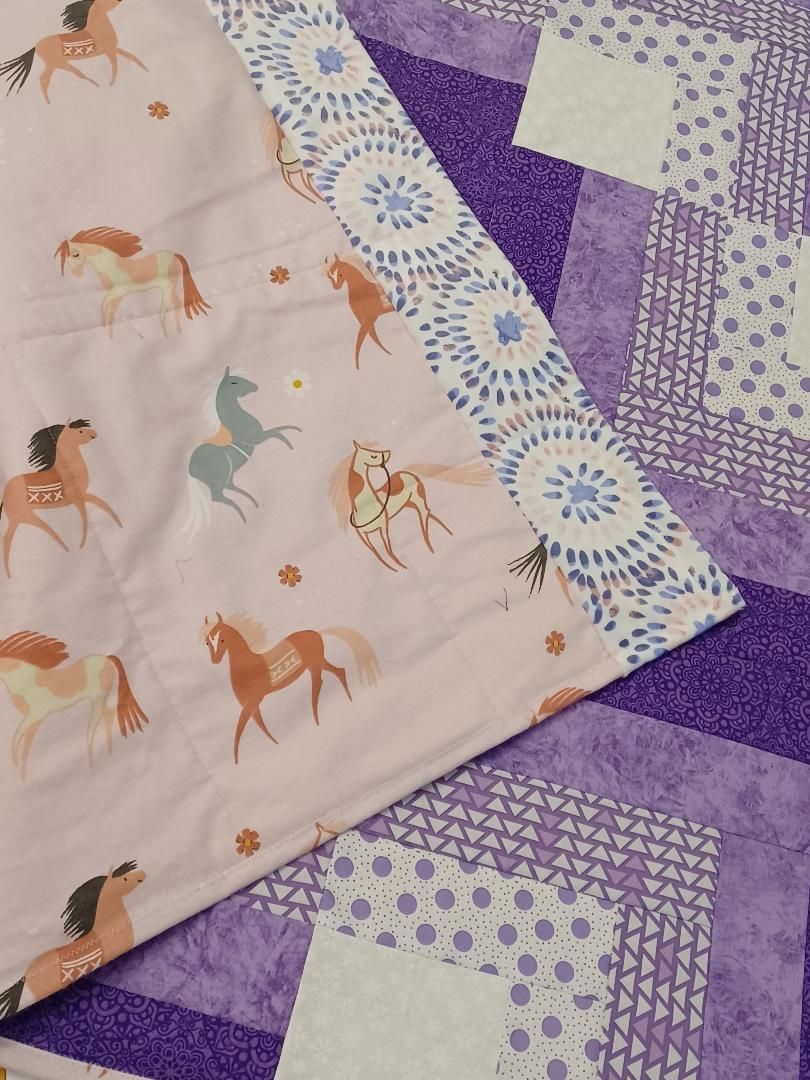 Folded pink and purple patterned fabrics with horse prints and geometric designs