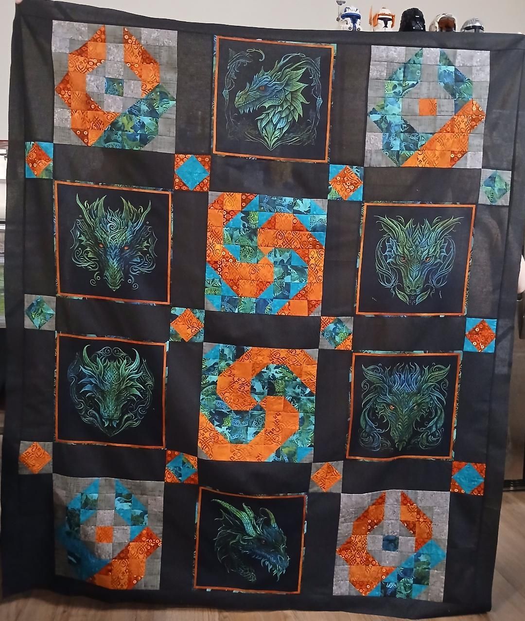 Quilt with black background, featuring teal, orange, and blue swirling square blocks in a grid.
