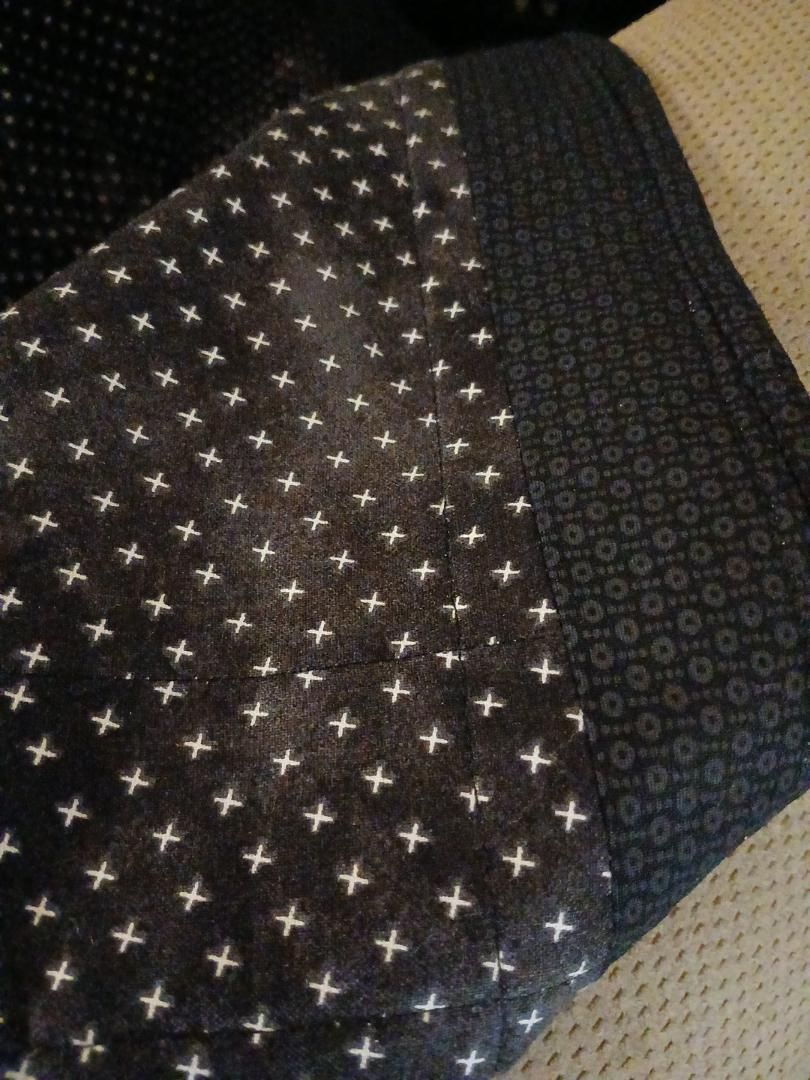 Patterned black and beige fabric with small white star-like dots and circular motifs