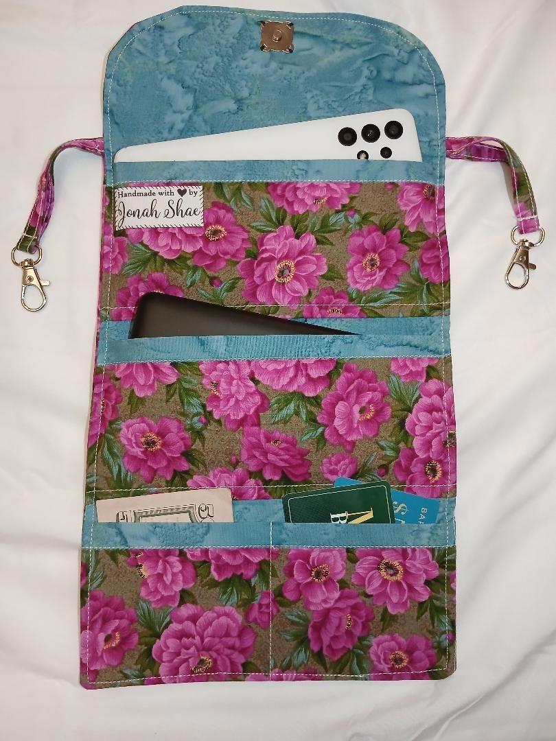 Floral fabric phone pouch with strap, white top panel, and zippered front pockets