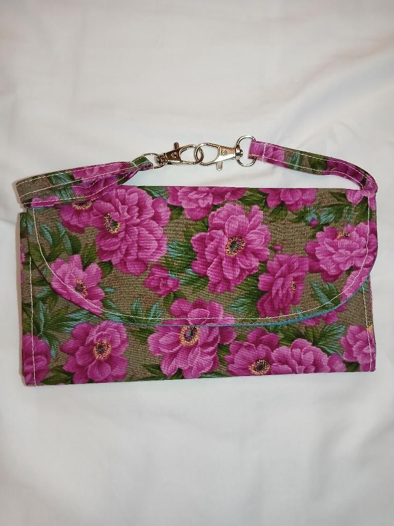 Pink floral clutch purse with matching strap on a white background