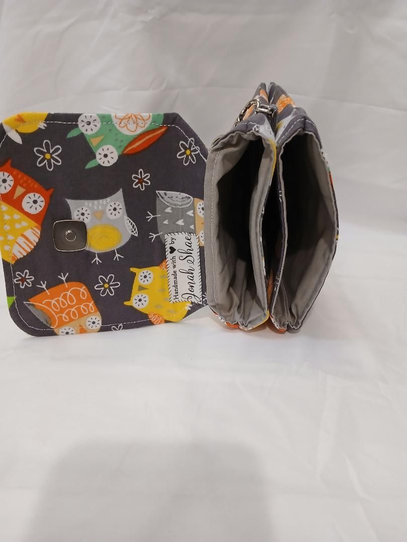 Patterned fabric wallet and folded coin purse in gray, orange, and white on a white background