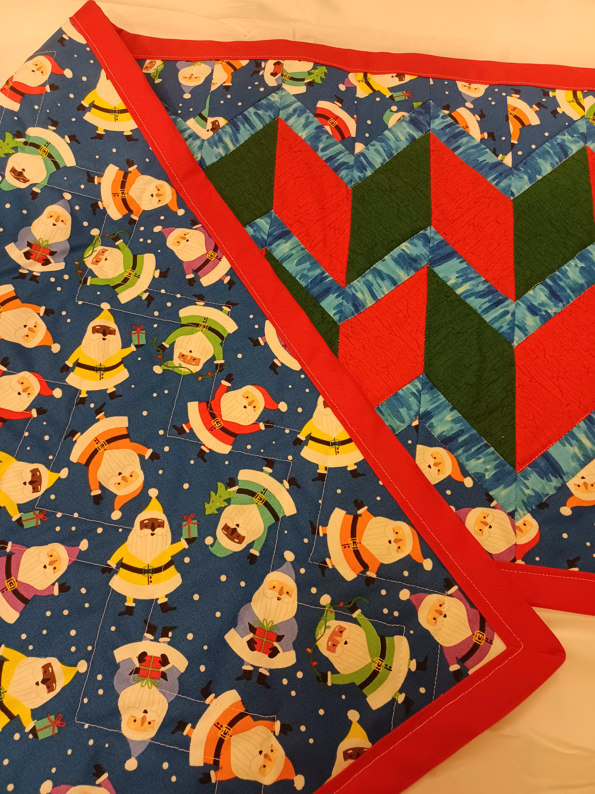 Colorful quilt with red borders, blue background, and small gnome figures in a repeating pattern