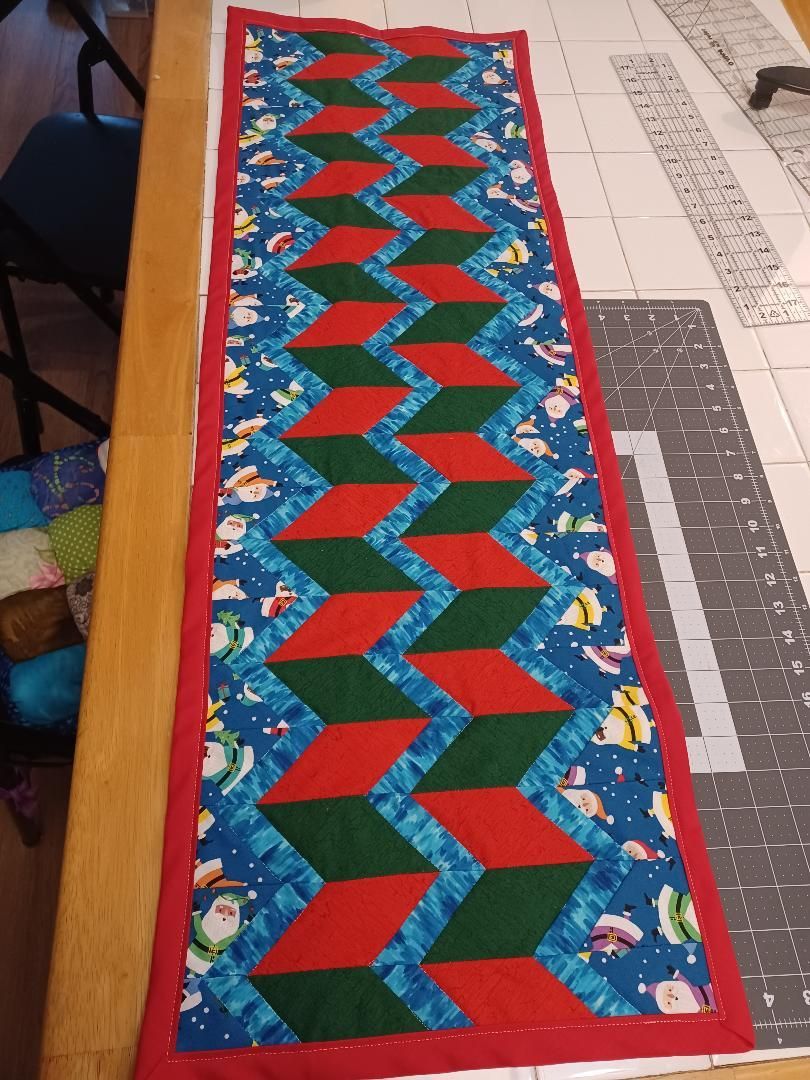 Colorful quilted table runner with red, green, blue and floral geometric pattern on a desk