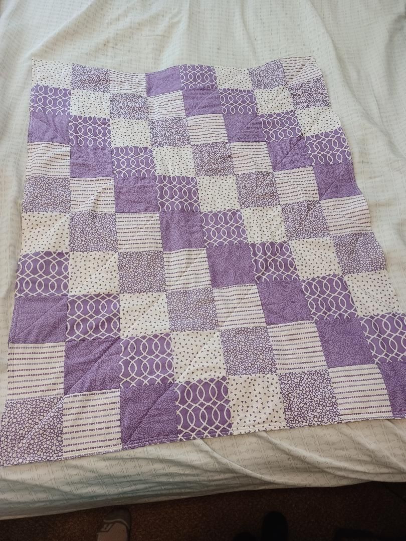 Purple and white patchwork quilt on a bed