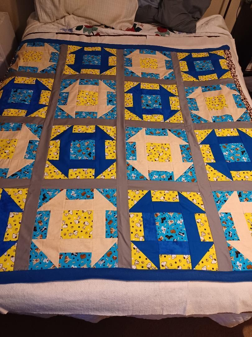 Colorful patchwork quilt with blue, yellow, and tan geometric squares spread on a bed