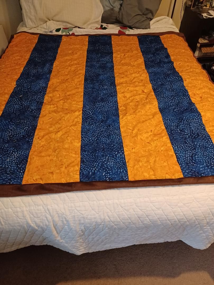 Blue and orange striped woven blanket spread across a bed